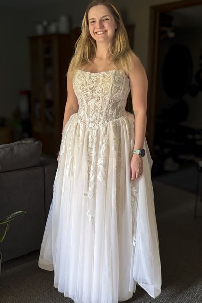 Client wearing an embroidered wedding dress with a full tulle skirt, front view